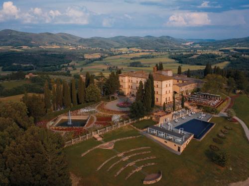 卡索莱德尔萨Castello di Casole, A Belmond Hotel, Tuscany的享有大楼空中景致,设有网球场
