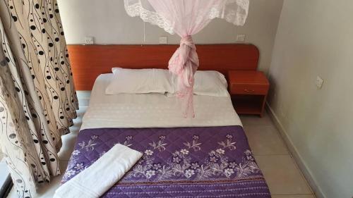 金贾Arise Africa International Christian Guesthouse的一间卧室配有一张带紫色和白色毯子的床