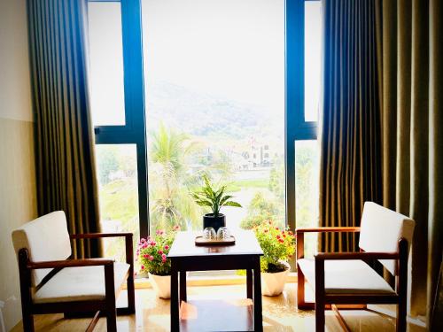 头顿An's Home Hotel Vũng Tàu的窗户前设有2把椅子和1张桌子的房间