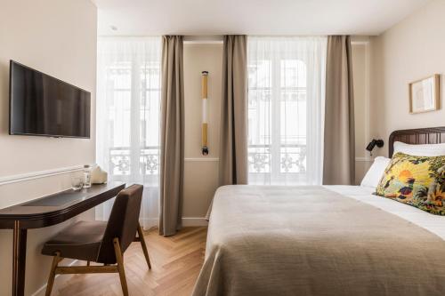 巴黎Hôtel Chamar的酒店客房配有一张床、一张书桌和一台电视。