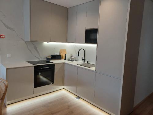 MoreiraOPORTO Suites的厨房配有白色橱柜、水槽和炉灶。