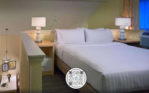 孟菲斯Sonesta Simply Suites Memphis East Poplar Pike的酒店客房,配有一张床、两张桌子和两盏灯