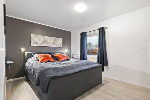 苏特兰Solhøgda的一间卧室配有带橙色枕头的床和窗户。