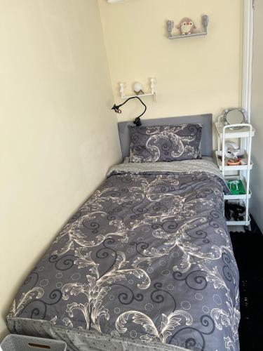 伦敦Quaint and Serene Single room的卧室配有一张带灰色和白色棉被的床