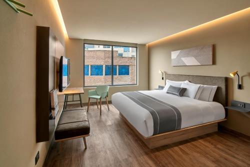圣路易斯波托西City Express Plus by Marriott San Luis Potosi的配有一张床、一张书桌和一扇窗户的酒店客房