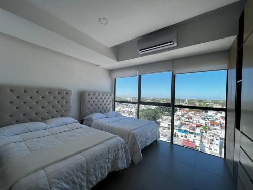 比亚埃尔莫萨Departamento Torre JR Premier Tabasco 2000的一间卧室设有两张床和大窗户