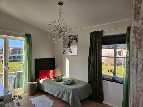 勒托普Trevlig fritidshus på Norra Öland的一间卧室配有一张带红色枕头的床和吊灯。