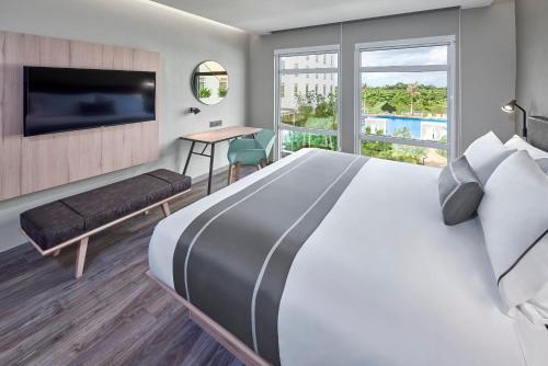 坎昆City Express Plus by Marriott Cancun Aeropuerto Riviera的酒店客房设有一张大床和一台电视机。