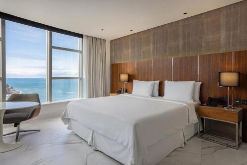 里约热内卢Hotel Nacional的卧室配有一张白色大床、一张书桌和窗户。