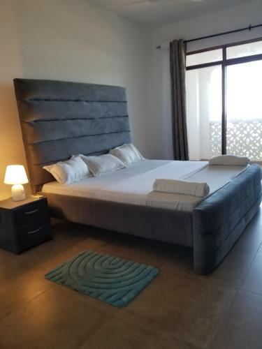 姆特瓦帕Almasi beach house的一间卧室设有一张大床和大窗户