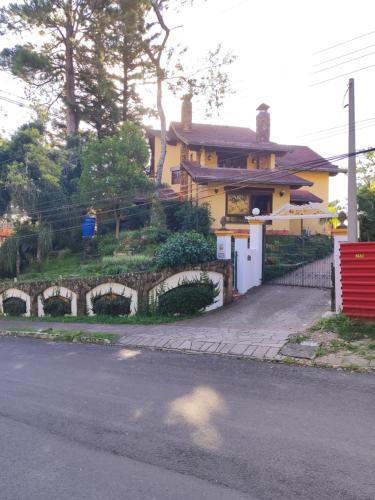 格拉玛多Pousada Oscar Magic Gramado的街道旁的黄色房子,带有石墙