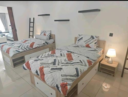 珍南海滩M-Residence的一间卧室设有两张床和一盏灯,位于地板上