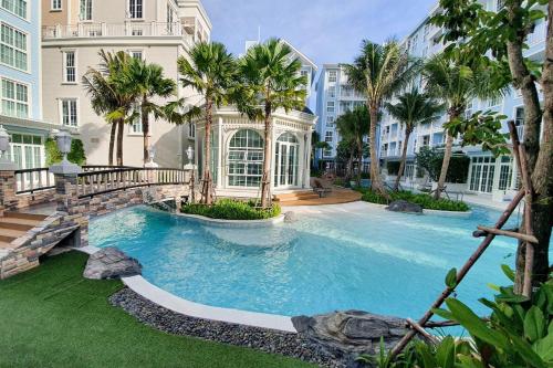 纳仲天Grand Florida芭提雅私家海滩花园公寓E206的一座棕榈树和建筑的大型游泳池