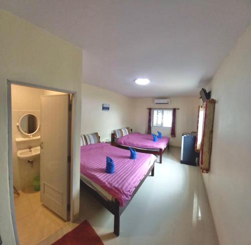桑卡武里Baan Dongsak River view的配有粉红色床单和蓝色枕头的客房内的两张床