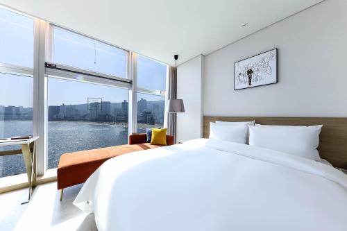 釜山Ocean 2 Heaven Hotel的一间卧室设有一张大床和一个大窗户