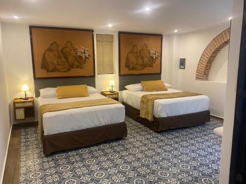 马萨特兰Hotel Tierra Marina Centro Historico的两张位于酒店客房的床,墙上挂有绘画作品