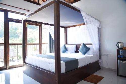 埃拉Ever Breeze Ella Hotel的一间卧室配有一张带白色床单和蓝色枕头的天蓬床。