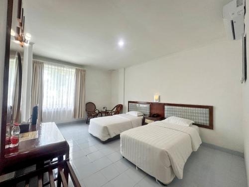 SibolgaHotel Wisata Indah Sibolga的酒店客房配有两张床和一张书桌