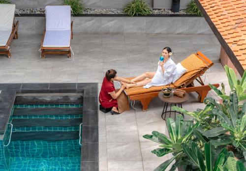 曼谷茉莉城市酒店 (Jasmine City Hotel Bangkok)的两个女人坐在游泳池旁的长凳上