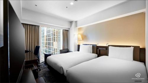 东京Daiwa Roynet Hotel Nishi-Shinjuku PREMIER的酒店客房设有两张床和窗户。