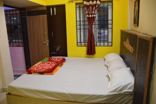 埃尔加德Amudha Hotels & Restaurant的一张大床,位于设有黄色墙壁和窗户的房间