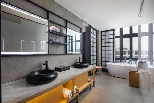 广州广州白云机场空港暻阁酒店 的浴室配有两个盥洗盆和浴缸。