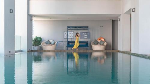 曼谷曼谷茉莉花59号酒店 (Jasmine 59 Hotel Bangkok)的穿着黄色衣服的女人在游泳池旁边走