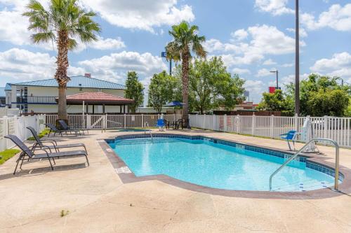 金斯兰Microtel Inn & Suites by Wyndham Kingsland Naval Base I-95的一个带椅子的游泳池,棕榈树