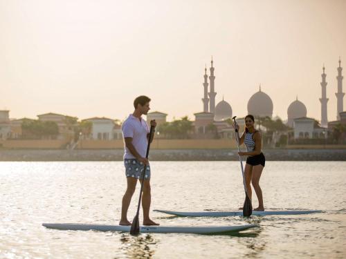 阿布扎比费尔蒙特巴布铝巴哈尔酒店的两个人站在水中的桨板上