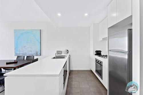 悉尼2 beds luxury apartment in the heart of chatswood12的白色的厨房配有不锈钢冰箱