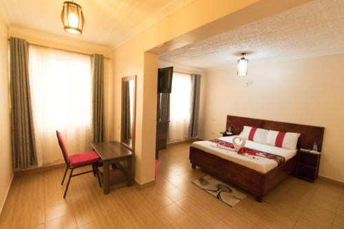纳纽基Africa One Hotel的卧室配有1张床、1张桌子和1把椅子