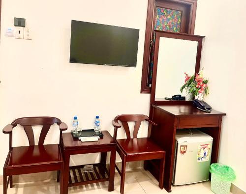 胡志明市DINH DINH 2 AIRPORT HOTEL的一间设有两把椅子、一张桌子和一面镜子的房间