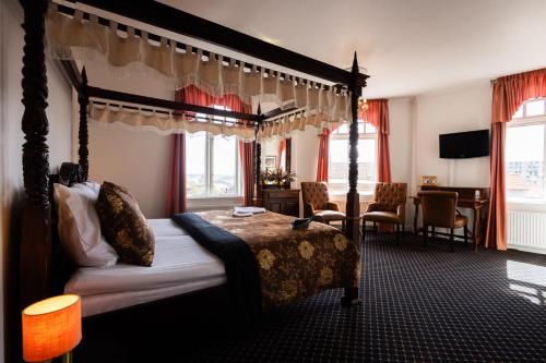 科灵Milling Hotel Saxildhus的一间卧室配有一张天蓬床和一张书桌