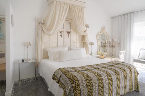 科英布拉CoimbraAmeias的白色卧室设有一张带天蓬的大床