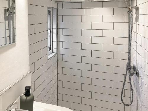 AddinghamLittle Plumtree的浴室内铺有白色瓷砖并配有水槽的淋浴间