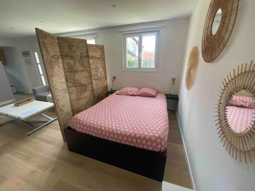 弗朗孔维勒La maisonnette的一间卧室配有一张带床头板和镜子的床