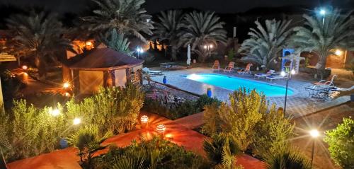 扎古拉Oasis Tilogui的游泳池设有凉亭,晚上种植棕榈树