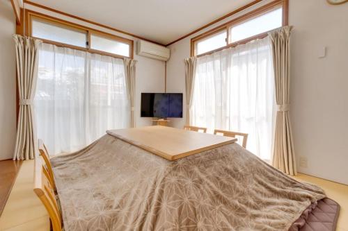 松本Forest Agata的客房设有桌子、两个窗户和一台电视机