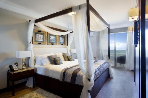 马卡埃皇家亚特兰大马卡埃酒店的一间卧室设有天蓬床和窗户。