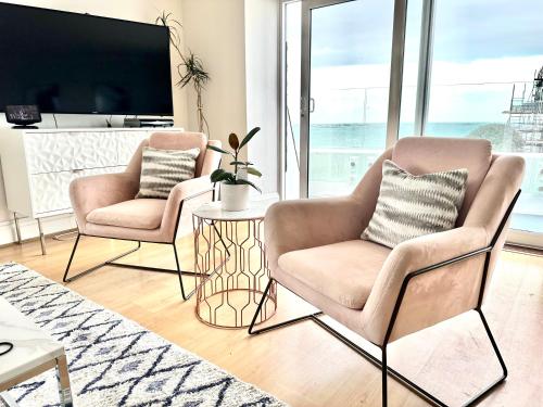 圣赫利尔泽西Eden Hotel - Beach Apartments & Suites的客厅设有两把椅子和一张桌子,配有电视