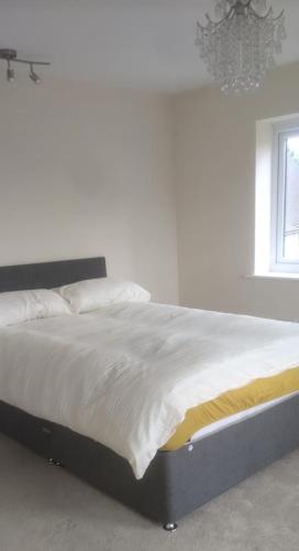 特尔福德Telford Guest House 1的卧室内一张带白色床单和吊灯的床