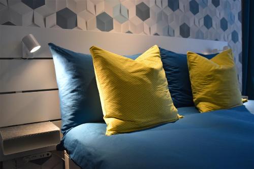 锡永Chambre d'hôte Valère的一张蓝色的床,上面有两个黄色枕头