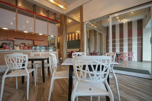 巨港Residence 8的餐厅设有白色的椅子、桌子和柜台