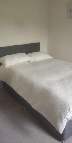 OltonSolihull Guest House 1的卧室内的一张带白色床单和枕头的床