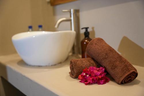 肯杜瓦Kendwa Breeze Bungalows的浴室柜台设有水槽、两条毛巾和鲜花