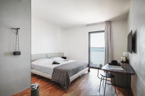 西尔米奥奈AQVA Boutique Hotel (Adults Only)的一间卧室配有一张床、一张书桌和一个窗户。