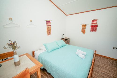 La HuaicaTantakuy Eco Experience Hotel的一间卧室配有一张蓝色的床和一张桌子