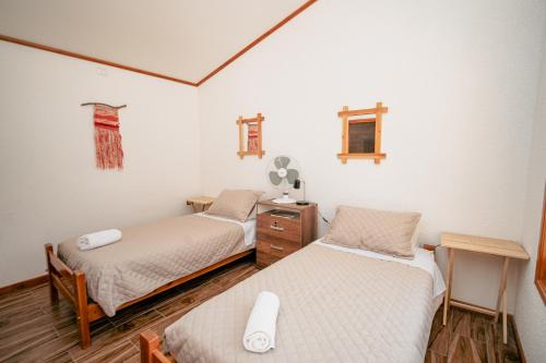 La HuaicaTantakuy Eco Experience Hotel的配有白色墙壁和木地板的客房内的两张床