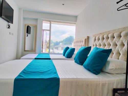 波哥大Hotel Batan 127的一间卧室配有一张带蓝色枕头的大床