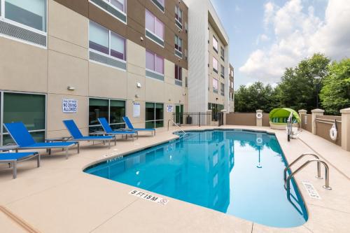 岩石丘Holiday Inn Express & Suites - Rock Hill, an IHG Hotel的一座带椅子的游泳池以及一座建筑